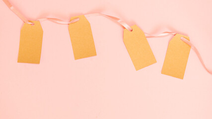 Clothes labels on pink satin ribbon on pink background