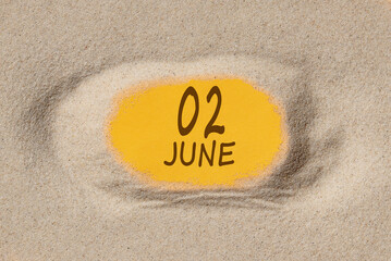 June 2 . 2th day of the month, calendar date. Hole in sand. Yellow background is visible through hole. Summer month, day of the year concept