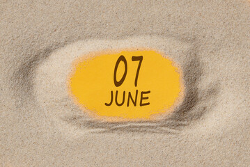 June 7 . 7th day of the month, calendar date. Hole in sand. Yellow background is visible through hole. Summer month, day of the year concept
