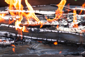 Metal brazier with burning wood and coals in nature on a bright summer sunny day. Bonfire with red...