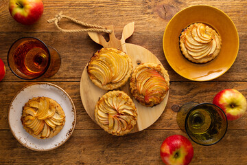 Mini Apple pie tartlets with walnut on wooden table. Delicious dessert for autumn winter dinner.Top view.