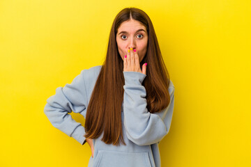 Young caucasian woman isolated on yellow background shocked, covering mouth with hands, anxious to discover something new.