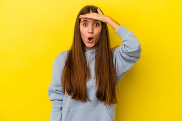 Young caucasian woman isolated on yellow background looking far away keeping hand on forehead.