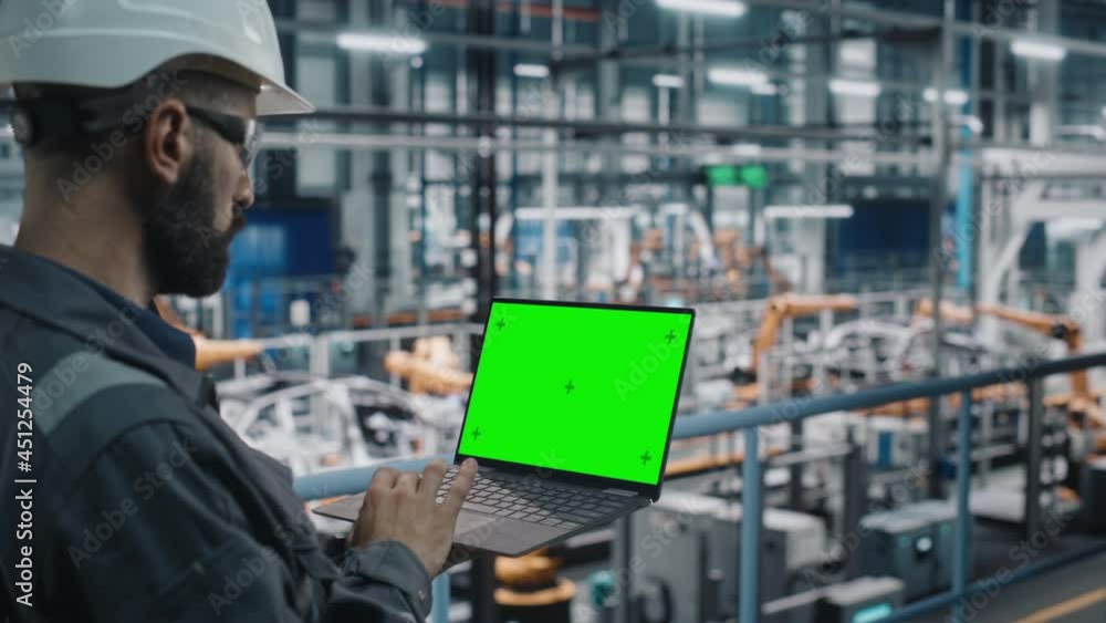 Aufkleber car factory engineer in work uniform using laptop computer with green screen mockup display. working
