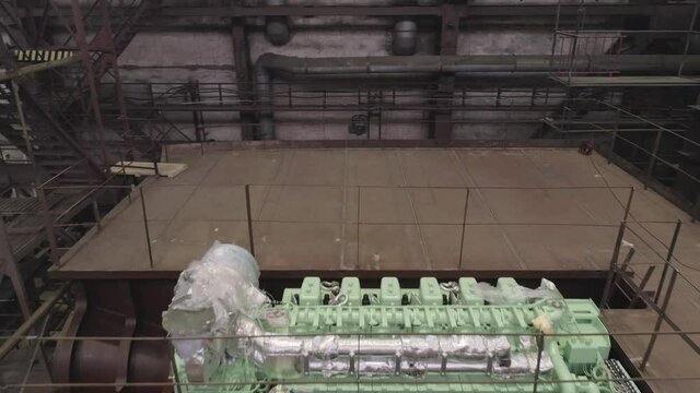 Modern green engine in hold of old repairing crab ship with empty deck standing in dry dock at industrial complex