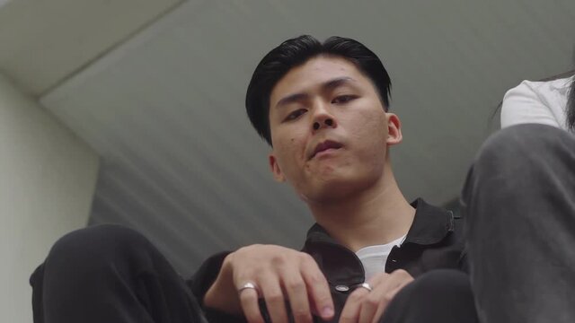  Cool and moody two asian freinds outside. Guy looks at camera dangerous in slow motion. Power confident young man. Asian Boy looking down at camera. Urban concept