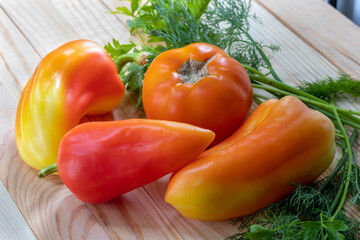 Set of fresh vegetables for salad: bell pepper, yellow tomato and spicy herbs - dill and parsley. Closeup, wooden background. Advertising background - for menu, on topics about fresh vegetables