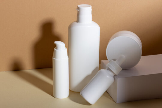 A set of female professional cosmetics for face and body care. Cosmetic tube with skin care product on beige background with hard shadows.