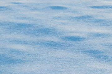 Snowy background, snowy surface with a clearly expressed texture of snow in the morning sun