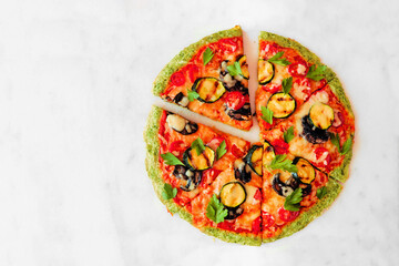 Healthy, gluten free broccoli crust pizza with tomatoes, zucchini and mushrooms. Top view with cut...