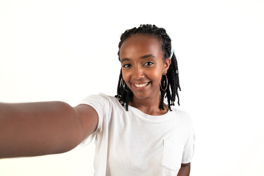 Self photo of a woman smiling looking at camera. Selfie picture. White background. African-Ethiopian black woman.