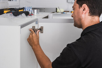 Worker adjusting the hinges of a kitchen cabinet