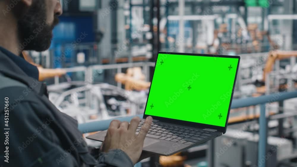 Poster car factory engineer in work uniform using laptop computer with green screen mockup display. working