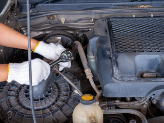 Mechanic holding a block wrench handle while fixing a car.