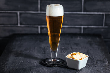 Glass of beer on a dark background with different snacks
