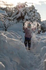 Kind spielt im tiefen Schnee und wirft Schnee in die Luft