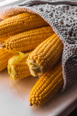 Yellow corn in a knitted bag on a white background. Eco friendly bag.