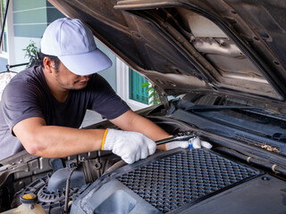 Mechanic holding a block wrench handle while fixing a car.