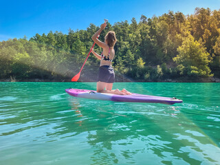Beautiful and strong woman on a sup board and enjoying turquoise transparent water in the lake....