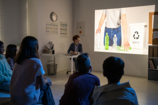 Schoolchildren Watching Video About Recycling Plastic Bottles In Dark Classroom