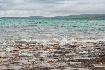 Dramatic scene with Sea waves, rocky seashore and clouds