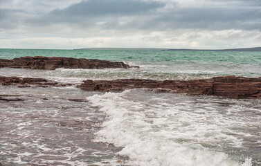 Dramatic scene with Sea waves, rocky seashore and clouds