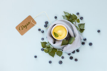 Dairy free, mango ice cream or frozen yogurt. Horizontal food composition with vegan, fruit ice cream, leaves and blueberries on a blue background with inscription vegan. Summer vacation food