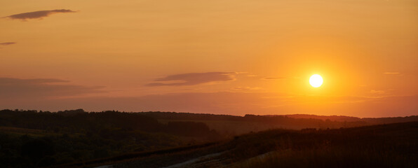 Fabulous panorama of a summer evening sunset in the clear sky. Orange color of the sky.
