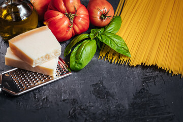 Ingredients for perfect Italian Spaghetti including pasta, basil, tomato, olive oil and parmesan cheese
