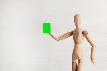 A wooden mannequin holds in his hand a green pass, a card, a smartphone with a cr code
  on a light background. Ban on infected patients when visiting public places. Pandemic, outbreak of disease.