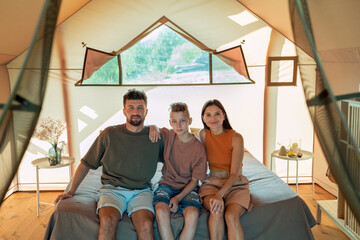 Young parents and their teenage son relaxing in glamping house while enjoying travel