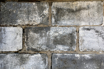 Old vintage retro style grey brick wall at street, decrepit with time. Abstract brick background and texture. Close-up.