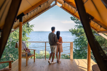 rear view of affectionate couple enjoying summer vacation in glamping house - obrazy, fototapety, plakaty