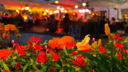night cafe flowers on table ,summer night city life yellow orange flowers on front cafe where...