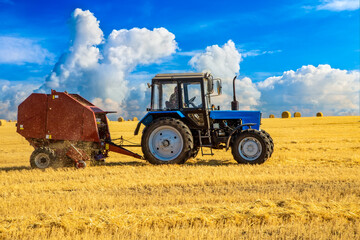Tractor with bale machine for harvesting straw in the field and making large round bales....