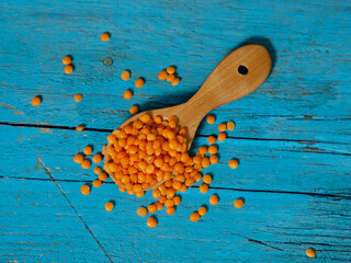 Red lentils in a wooden spoon on an old wooden table close-up. Vegetarian food.