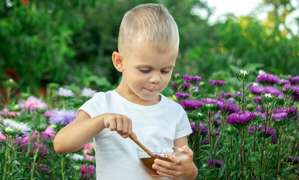 child eats honey in the garden.