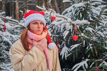 A woman coughs and holds a sore throat at a Christmas tree in winter nature on New Year Eve
