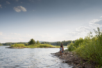 View of beautiful lake and blue sky with small clouds and family of three enjoying summer day
