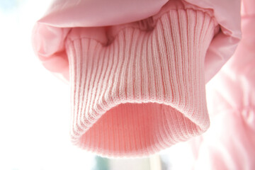 Pink sleeve of jacket or sweater, cuff for sealing. Narrowing sleeves on a light background, magky selective selective focus