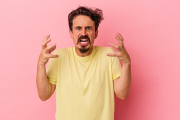 Young caucasian man isolated on pink background screaming with rage.