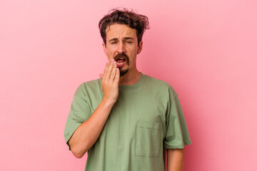 Fototapeta na wymiar Young caucasian man isolated on pink background yawning showing a tired gesture covering mouth with hand.