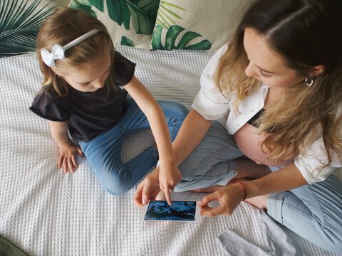 
pregnant woman looks at ultrasound images and shows them to her daughter