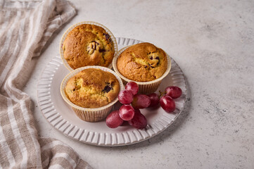 Homemade cupcakes with cherries and grapes on plate with napkin on light background, close up
