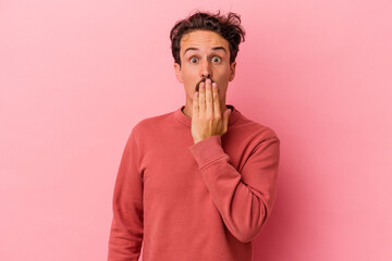 Young caucasian man isolated on pink background shocked, covering mouth with hands, anxious to discover something new.