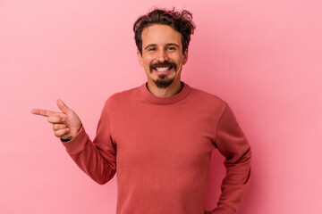 Young caucasian man isolated on pink background smiling cheerfully pointing with forefinger away.