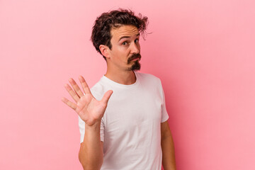 Young caucasian man isolated on pink background rejecting someone showing a gesture of disgust.