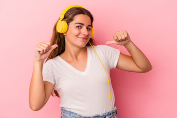 Young caucasian woman listening to music isolated on pink background  feels proud and self confident, example to follow.