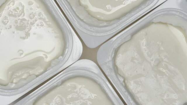 Cildren's Cottage Cheese In Four Plastic Containers Rotation On A Turntable White Plate. Close Up. Top View.