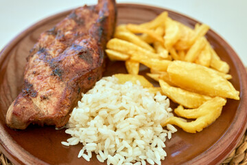 Plate of a veal cutlet with fried potatoes and rice.